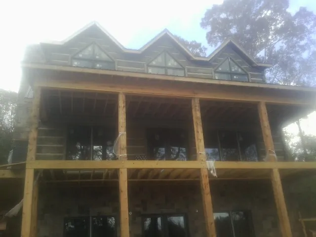 Dormers and porch framing on a large log home under construction — Roof Coating work by our crew in Truesdale