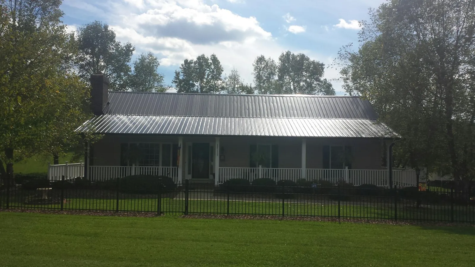 Gray metal roof on a brick ranch with a full width front porch — Gutter Guard Installation work by our crew in Truesdale