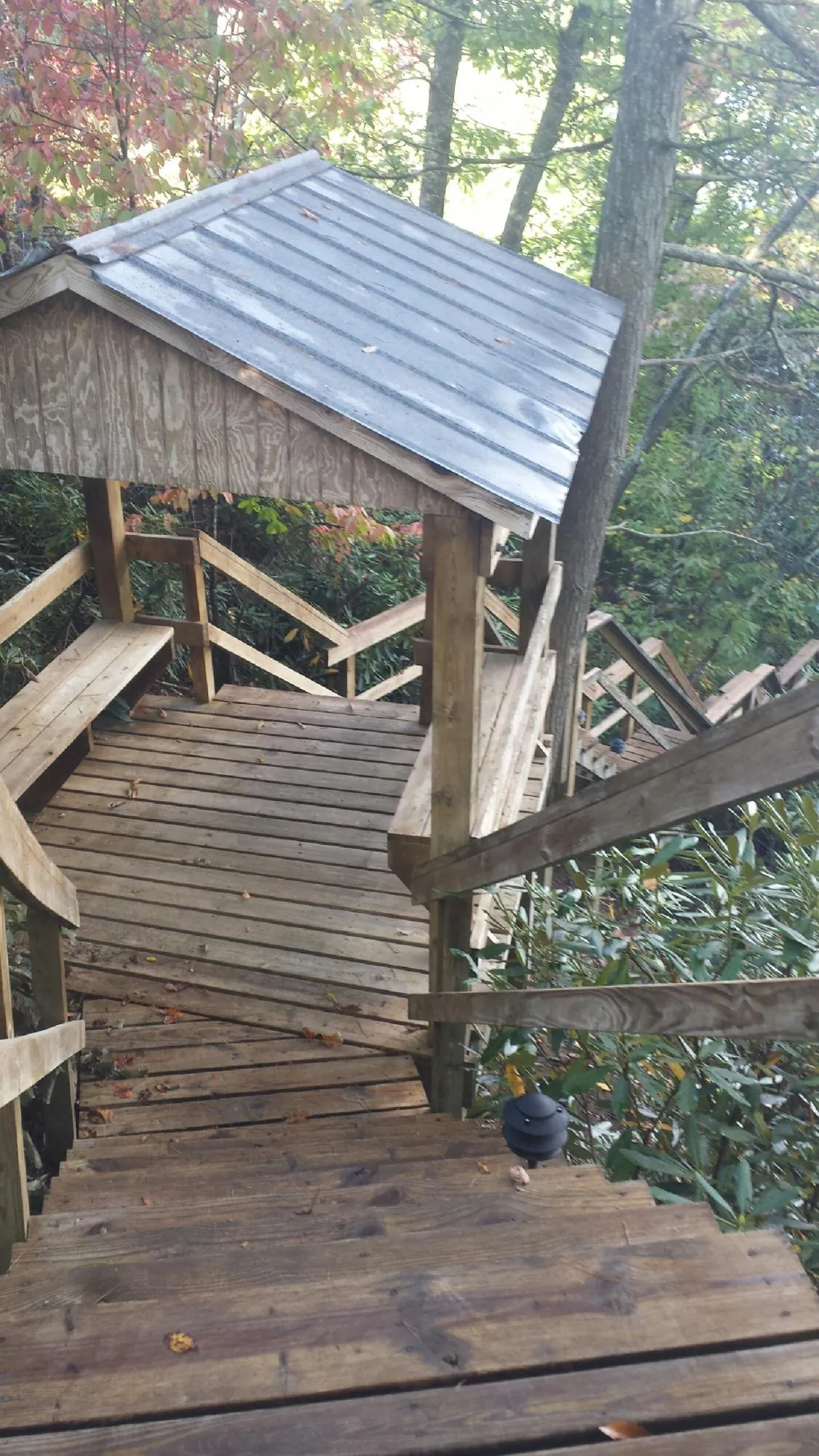 Metal roofed shelter over wooden steps on a wooded walkway — Skylight Repair & Installation work by our crew in Truesdale