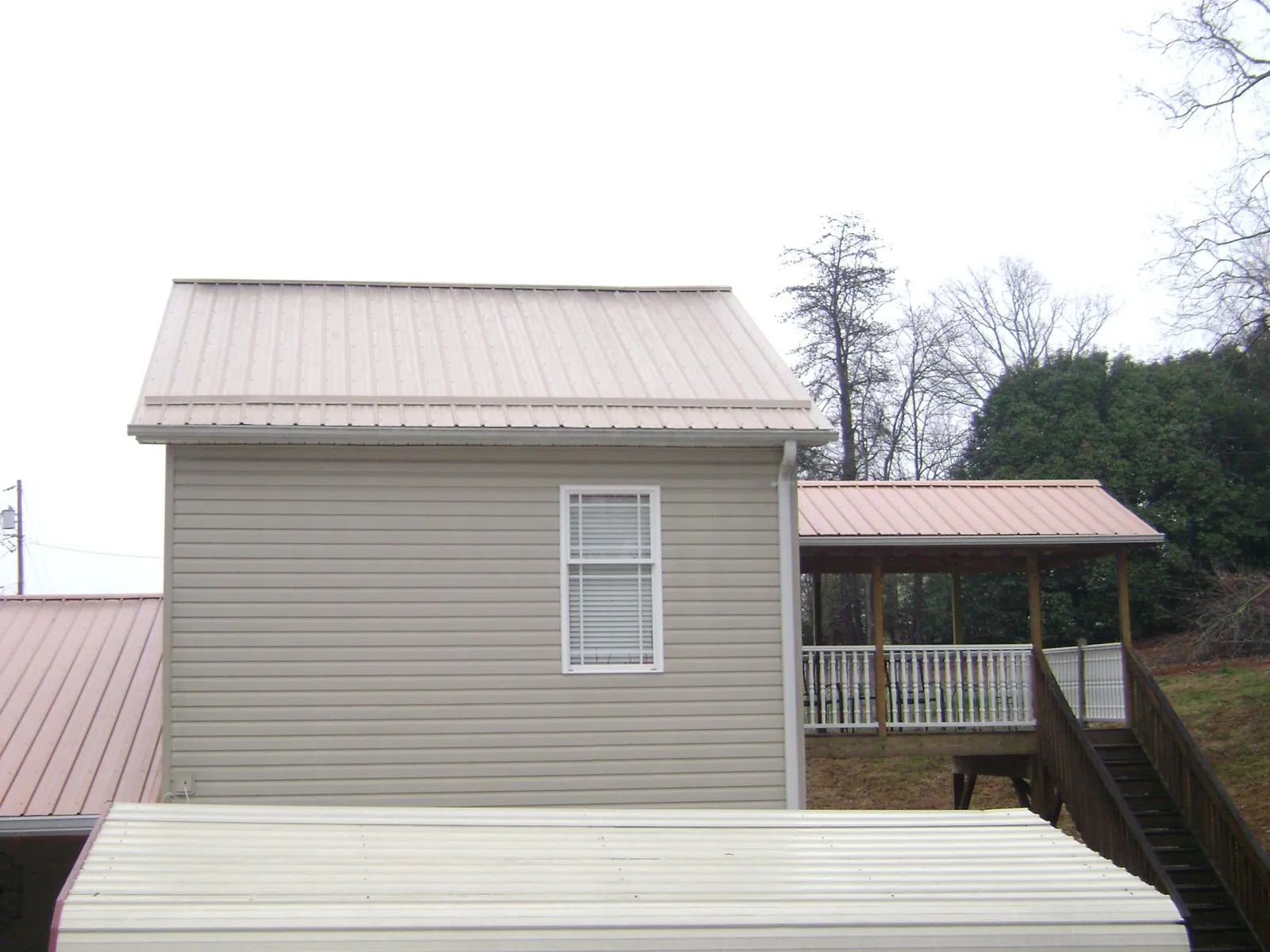 Tan metal roofs on a two story addition and attached porch, from a Roof Replacement job in Truesdale