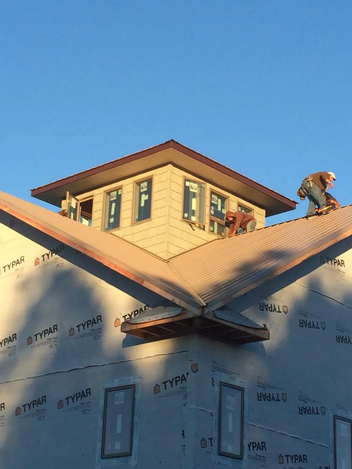 Roofers working around a rooftop cupola on a new metal roof at sunset — Roof Waterproofing in Truesdale by Roofing Brothers